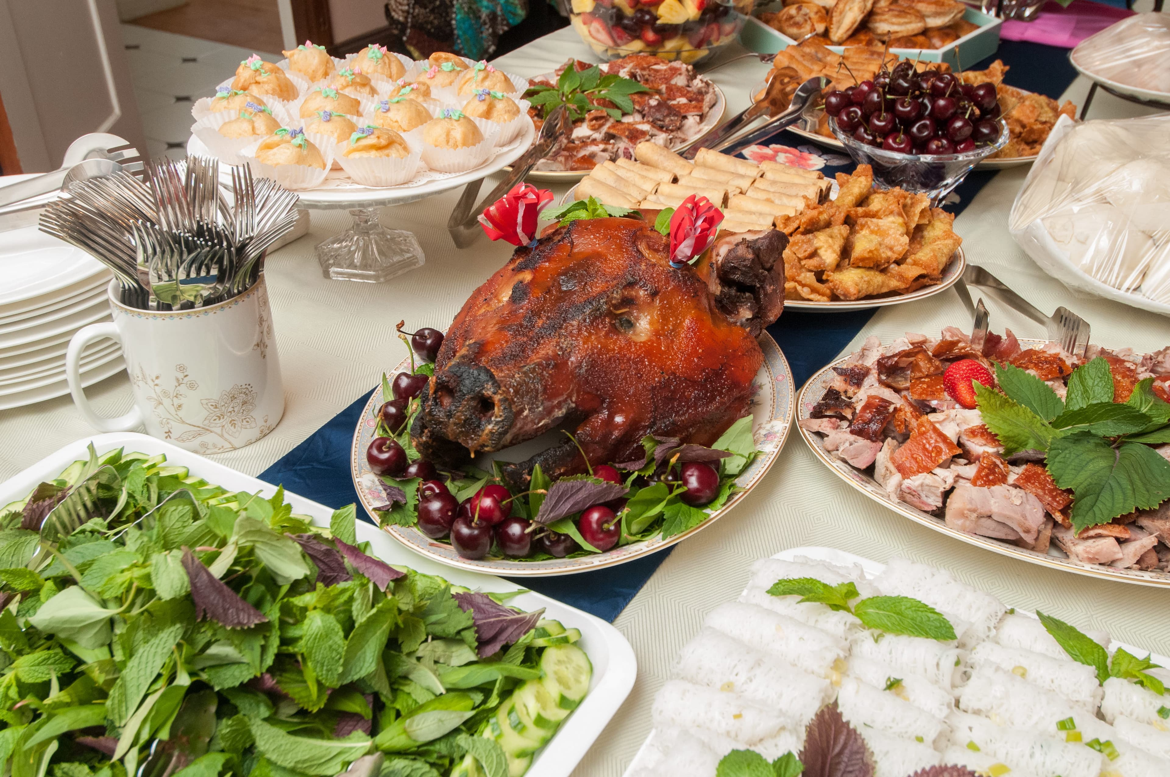 A spread of roasted pig, spring rolls, fruit, and other dishes laid out for the meal
