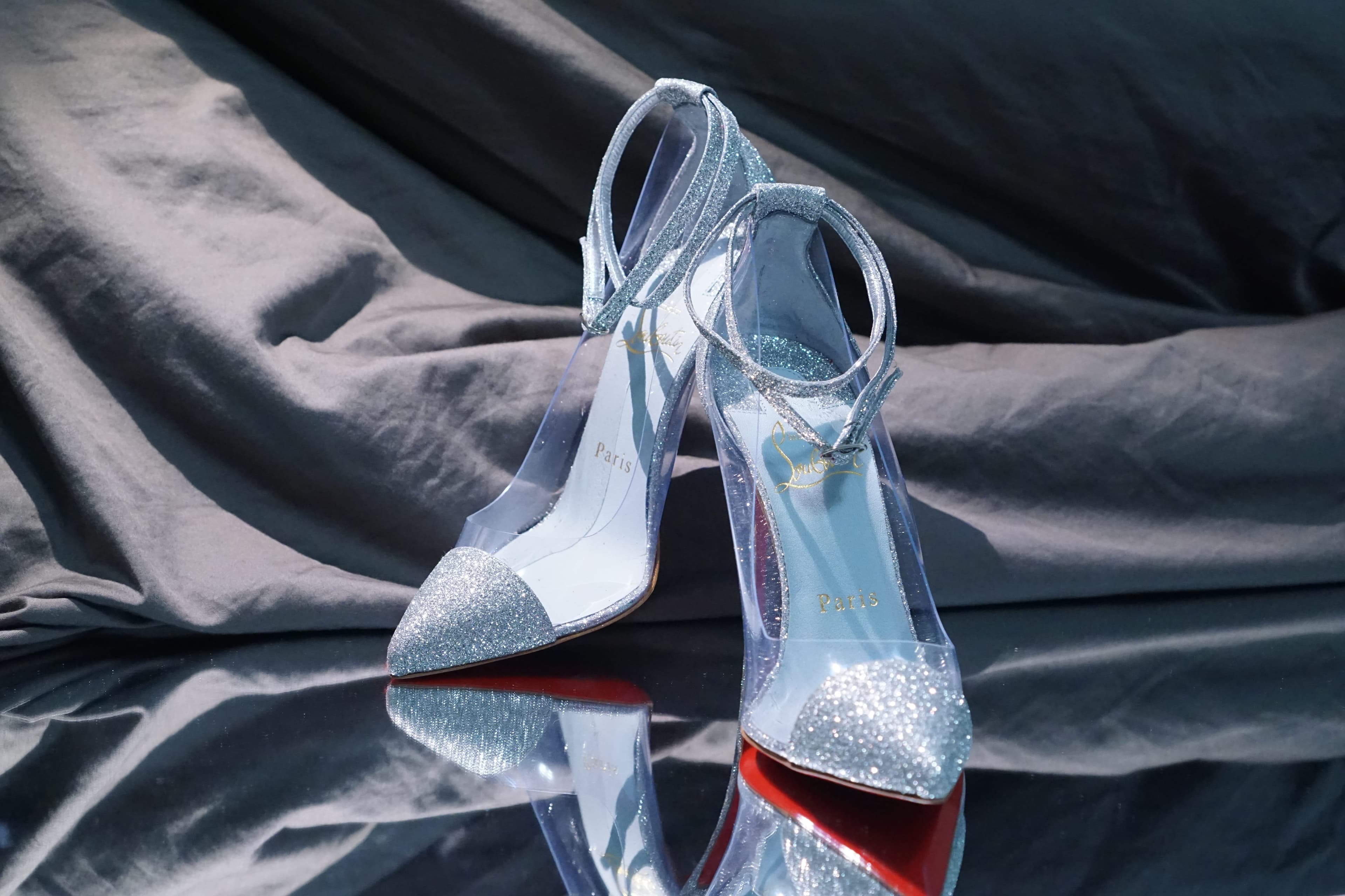Close-up of the glitter Louboutin heels with visible ankle straps and the red sole